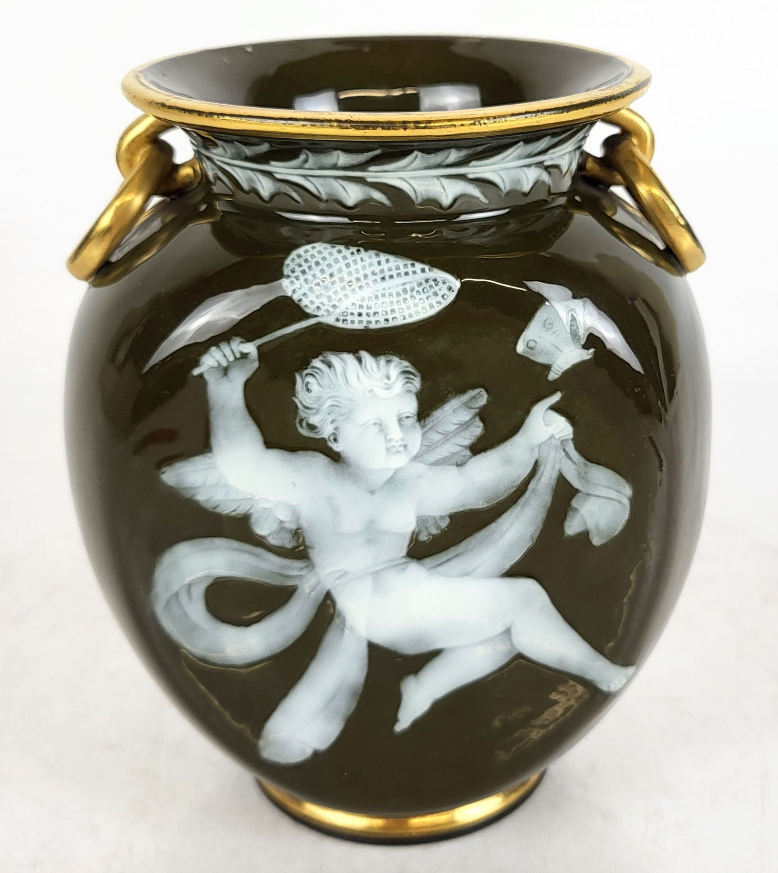 George Jones Pate-Sur-Pate Vase: George Jones pate-sur-pate vase by Frederick Schenck, English, 19th century, with a gilt lid and a centerpiece of a winged child holding a net beside a butterfly. Signed 'Schenck' under centerpiece. M
