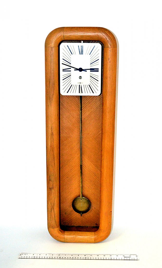 Howard Miller Wall Clock: Oak cased modern wall clock, one pendulum by Howard Miller, Zeeland, Michigan, USA. Some wear. [34" H x 11" L x 5" D]