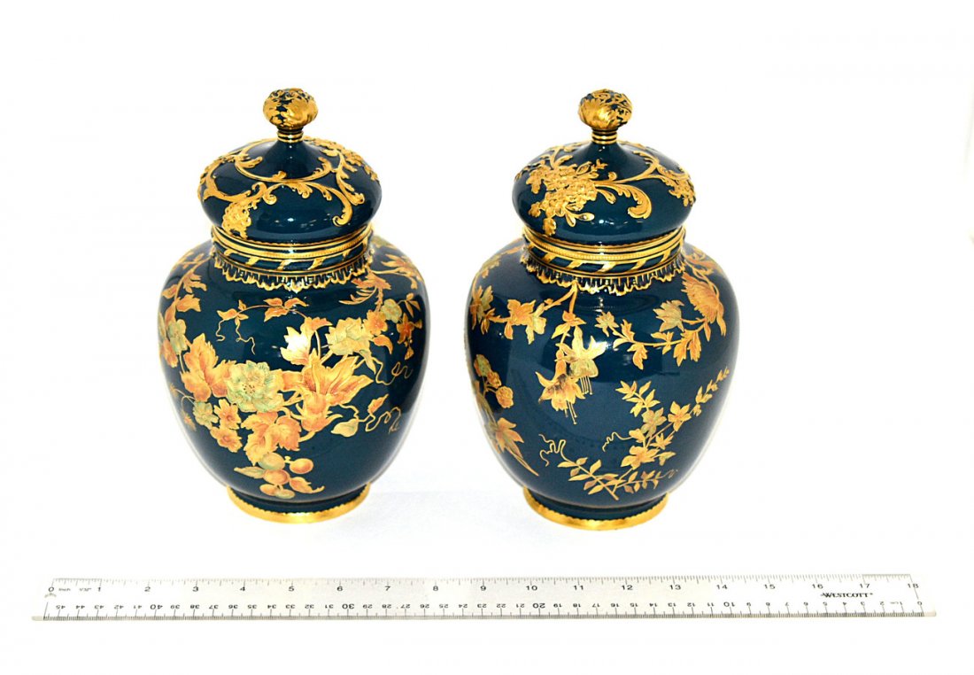Pair of Royal Crown Derby Urns: Pair of covered urns with hand-painted and gilt flower blossoms against a deep green background. Some gilding worn, otherwise complete. [9" Dia x 9 3/4" H]