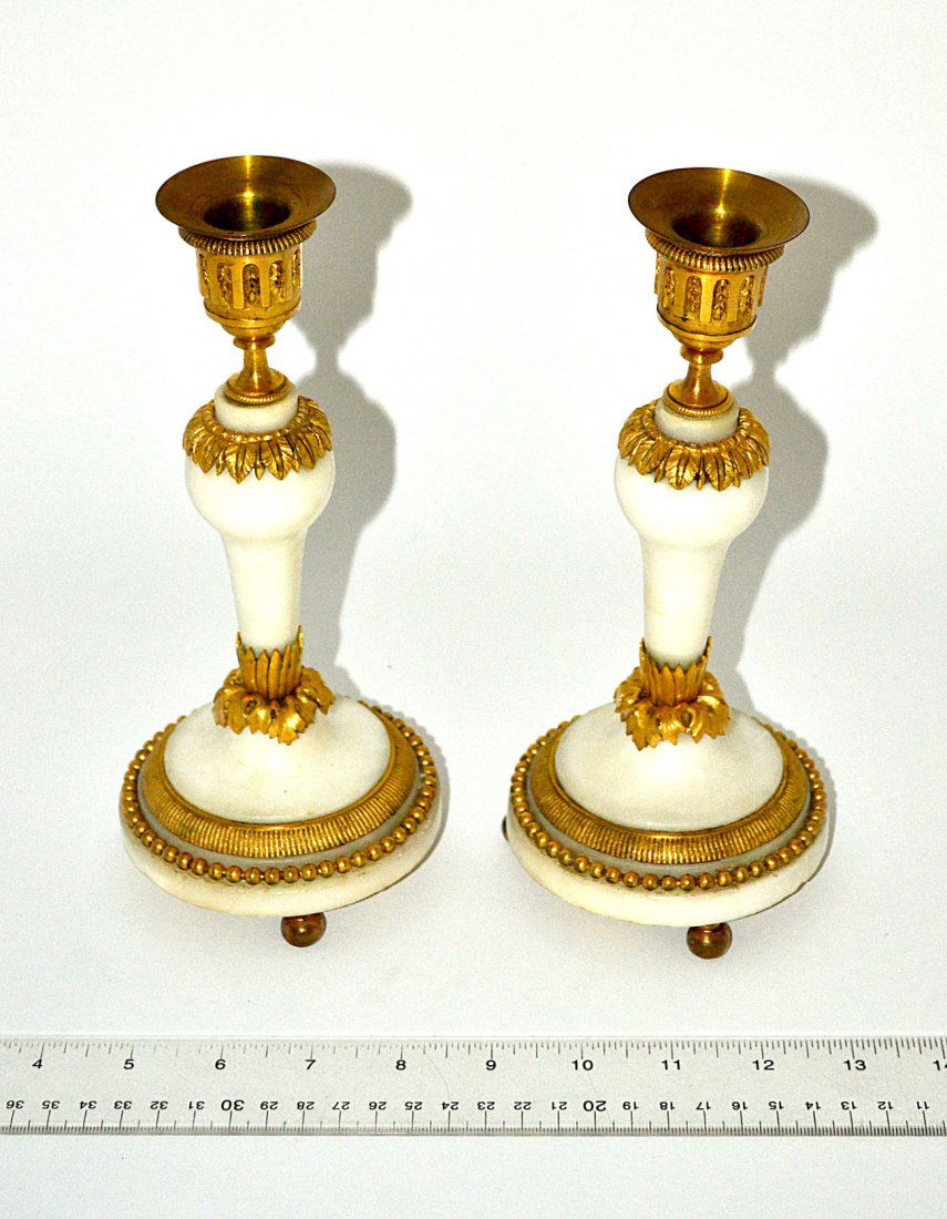 Pair of Alabaster Candlesticks: Pair of candlesticks with multiple gilt bronze accent bands and ball feet. Minor chips at base. [4" Dia x 9" H]