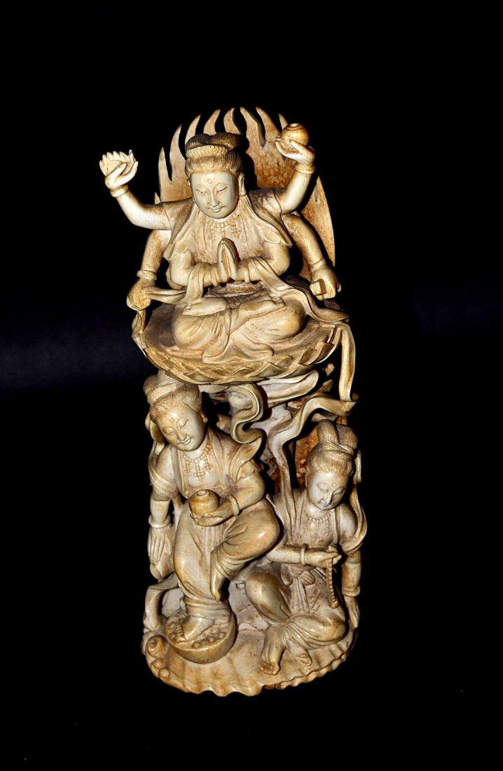 Asian Carved Ivory Buddhist Figural Group: Elaborate figural group depicting two figures below a Buddha with six arms seated on a lotus blossom, marked on back. [8 3/8" H]