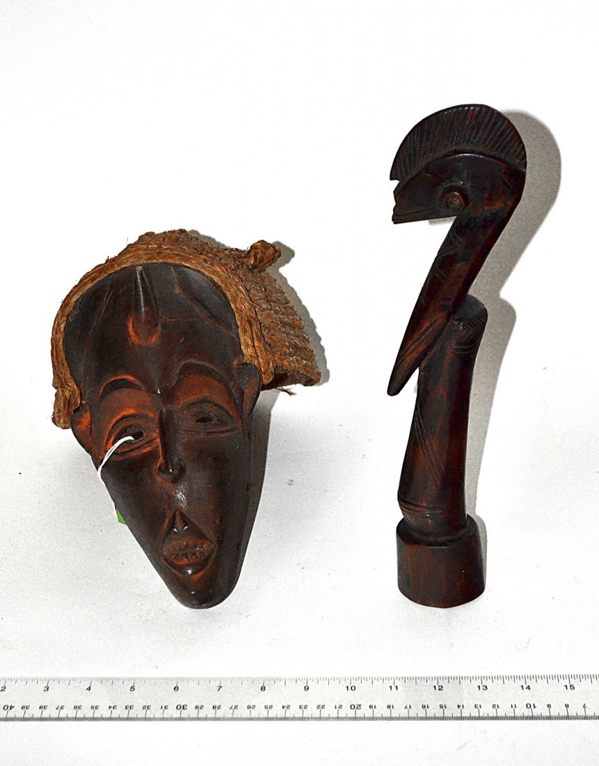 African Carved Wood Mask and Fertility Figure: Comprises 1.) Stylized mask with single horn protruding from forehead and wove grass hair [7 1/2"W x 10 1/2" D x 10"H]. 2.) Abstract geometric female fertility figure [ 2 1/8"W x 3"D x 12 3/4"H]. Mino