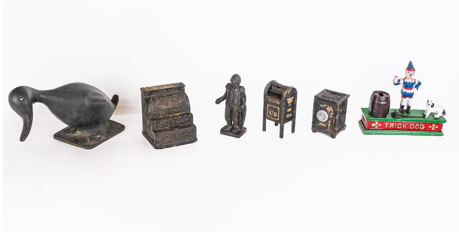 Six Cast Iron and other Articles: Group of cast iron and other articles, late 19th to mid 20th century, comprising a cast iron duck form doorstop, a cast iron mailbox, a cast iron penny bank in the form of a safe with a combination lo