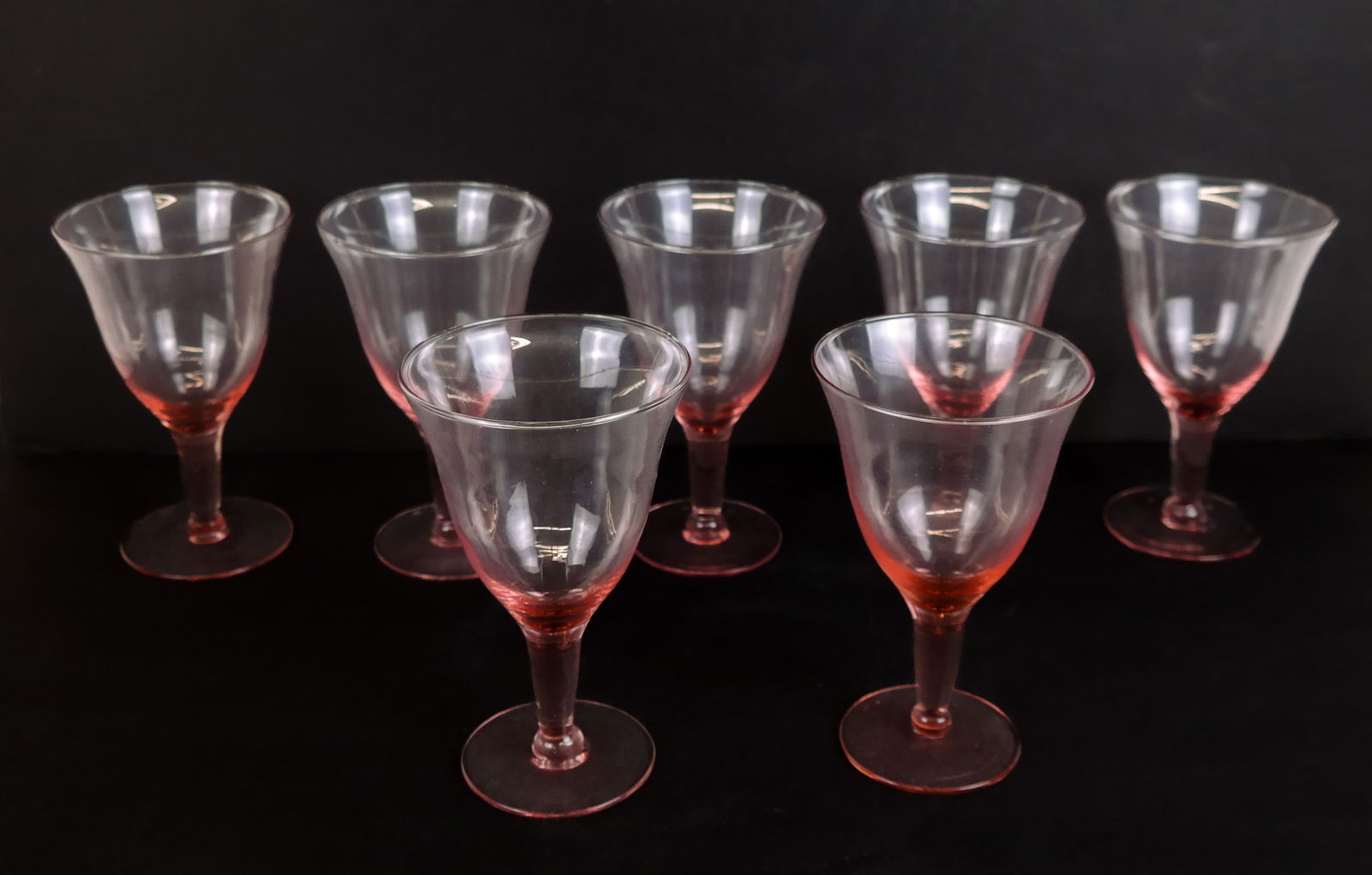 7 Blush/Peach Colored Glass Goblets: Set of 7 blush / peach colored glass stemware wine glasses. [6.25" H x 4" Diameter]. Overall condition is good.