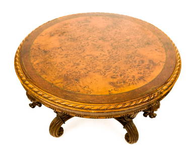 Neoclassical Carved and Burlwood Coffee Table: Neoclassical carved and burl topped coffee or center table, 20th century, with a book matched burlwood top, and carved border, over heavily carved and parcel gilt legs. [20" H x 33" Diameter]. Conditi
