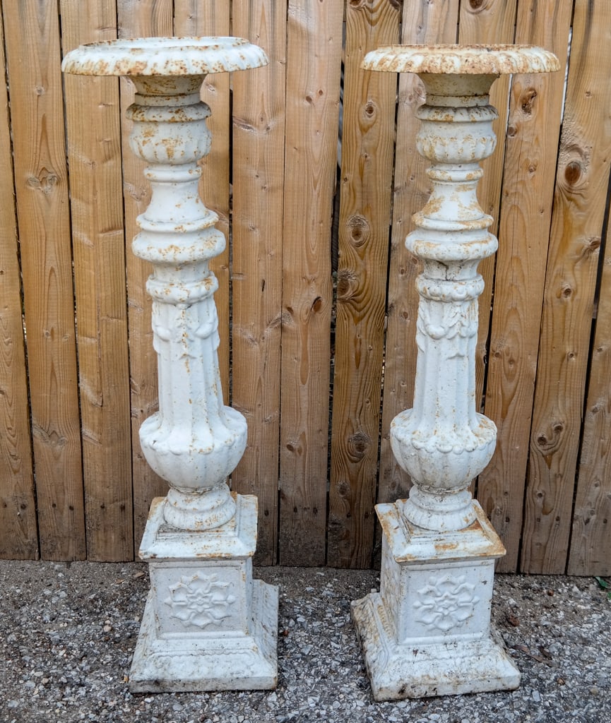 Pair Victorian Cast Iron Altar Sticks: Pair Victorian cast iron altar sticks, late 19th century, later painted white with swag decoration over a square base decorated with foliate cartouches. [27" H x 8" Diameter]. Condition is good with r