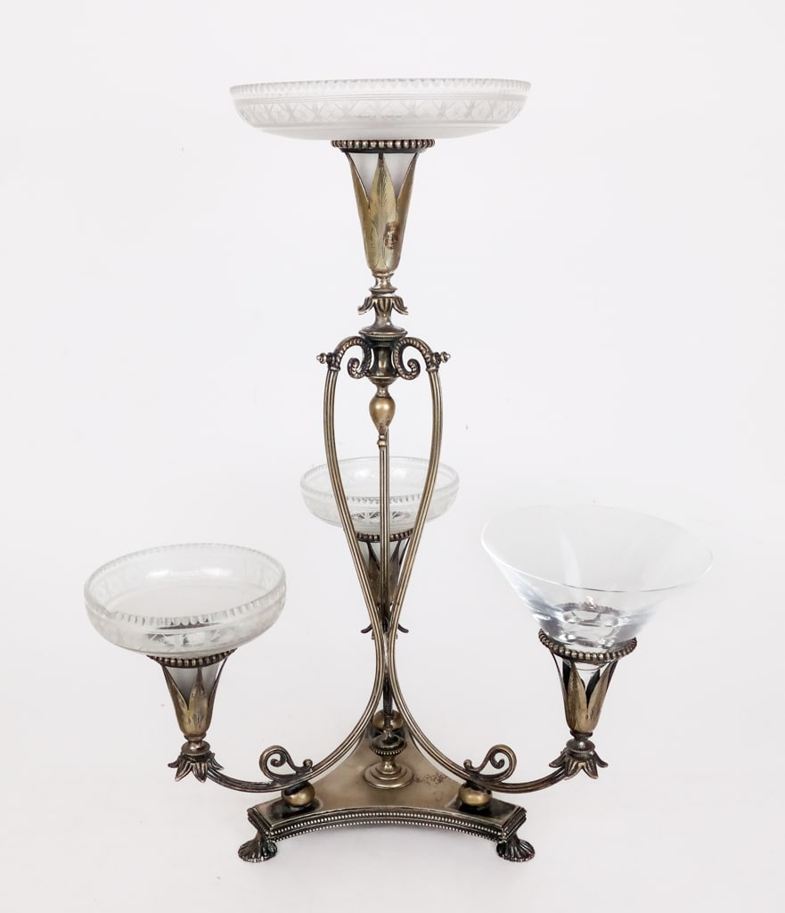 Silvered Brass and Glass Epergne: Neo-classical silvered brass and glass epergne, early 20th century, the lotus blossoms retaining glass dishes. [16" H x 13" W x 12" D"]. Overall condition is fair, losses to silver, one glass replaced