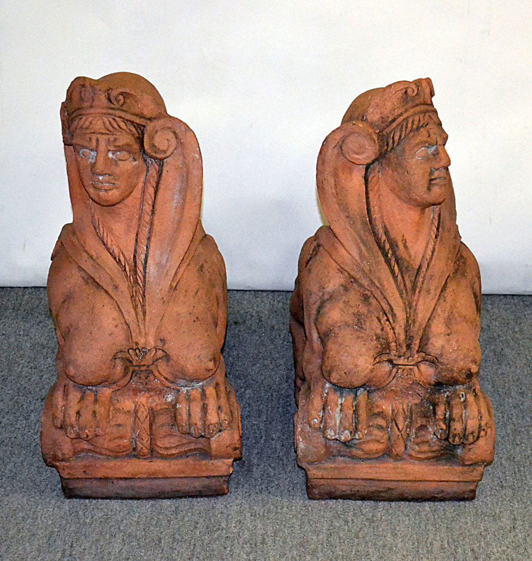 Pair of Antique Terra Cotta Sphinxes: Belle epoque architectural/garden elements, each with scrolling volute head dressings. Soiling and wear consistent with age. [11 1/2" W x 24" D x 24 1/2" H]