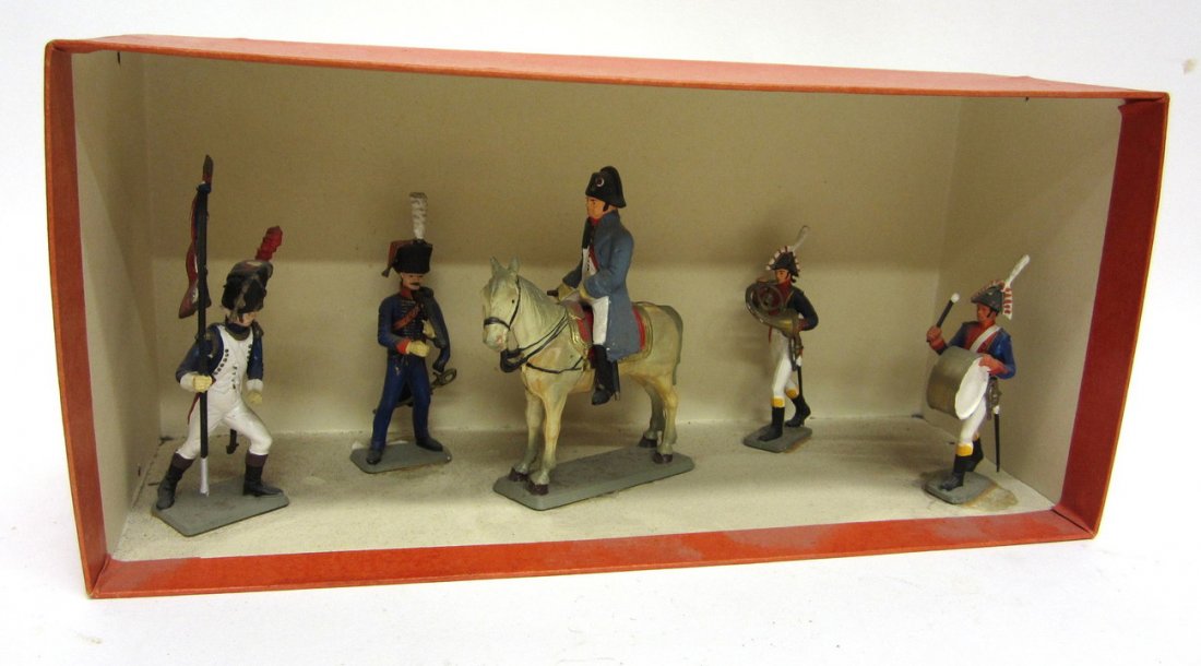 Group of Five Vintage Napoleonic Toy Soldiers: Comprises: French general on horseback, standard bearer, drummer, and horn player. Accompanied by a Prussian officer. All mounted within a cardboard box. All bear minor wear. [Tallest figure: 4" H]