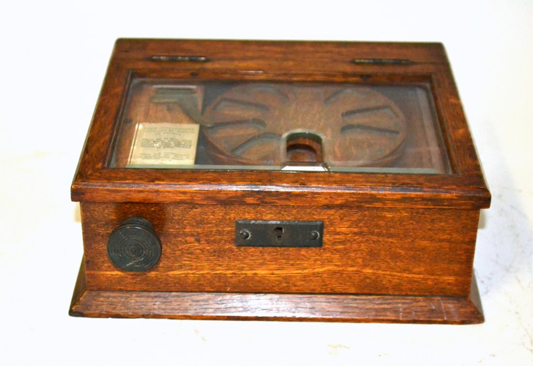 Antique Edwardian Oak Stamp Dispenser: Bears a coin activated revolving disc [mechanism not functioning] and hinged glass lid [with crack near opening]. As is. [9 3/4" W x 5 5/8" D x 3 5/8" H]