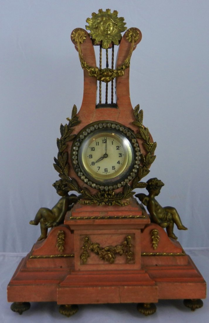 Bronze and Marble Lyre Shaped Clock: Antique Bronze and Marble Lyre shaped clock. Jeweled bezel with bubble glass. Sunburst atop the Lyre. Two bronze Putti sitting down, one on each side of the clock. All floral/leaf decoration is made o