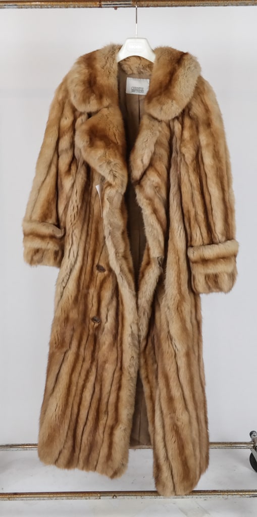 Christie Brothers Fur Coat: Christie Brothers fur coat with a notch collar, half-belt and pleat at back, with faux button hook and eye closure, and two invisible pockets. [Neck to hem: 51"; chest: 23", shoulder to shoulder: 20";