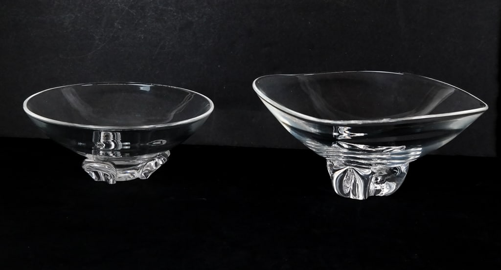 Two Steuben Crystal Bowls: Two Steuben crystal bowls on decorative feet, each marked Steuben to bases. [Larger: 4.75" H x 9.25" W x 9.5" D]. Condition to each is good with minor scratching at bases.