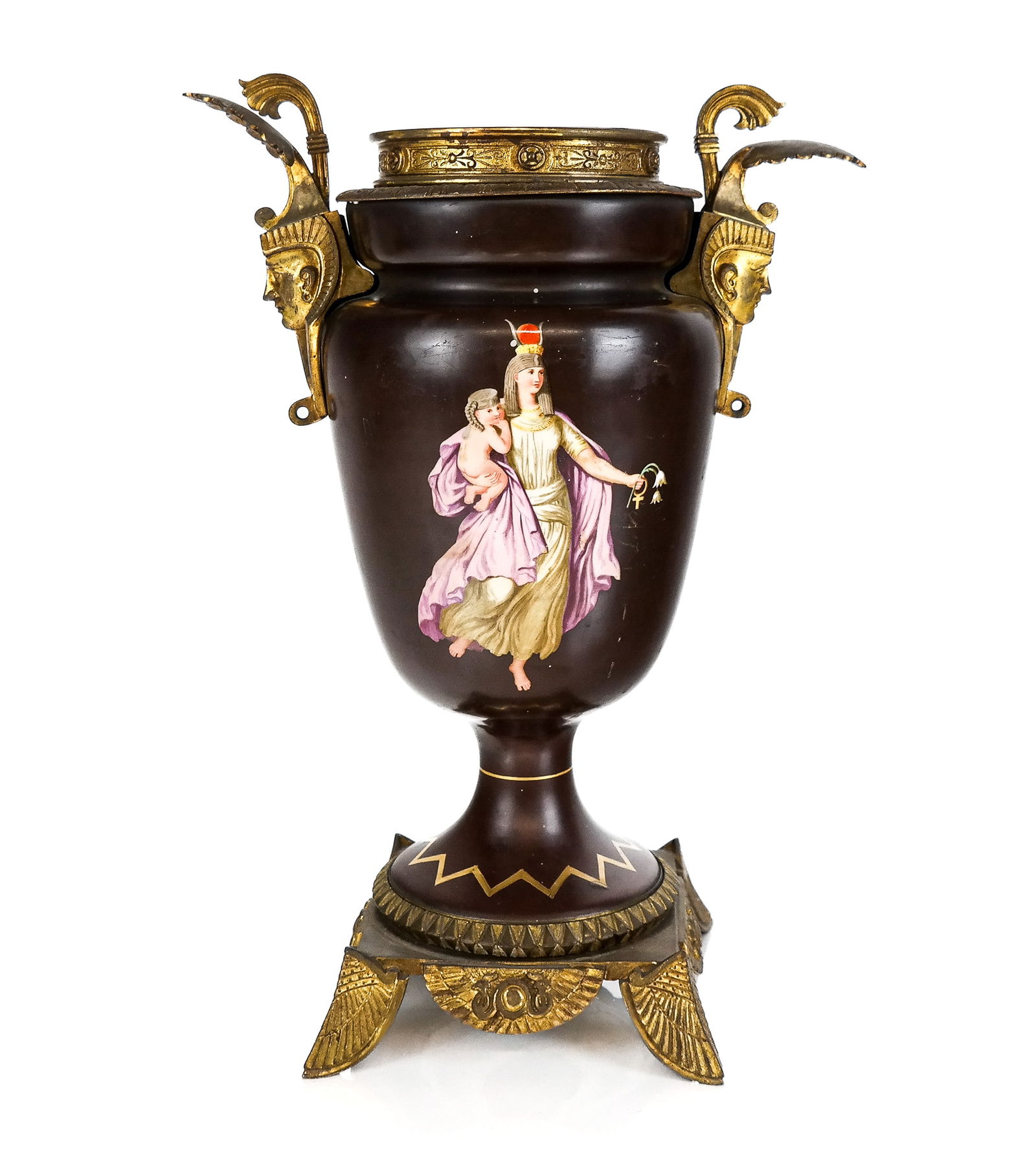 Egyptian Revival Bronze Mounted Urn: Egyptian Revival and bronze mounted urn, early 20th century, with hand-painted figures to each side, a gilt bronze lip, two mask form handles, and an Egyptian revival base. [14.75" H x 12" W x 6.5" D]