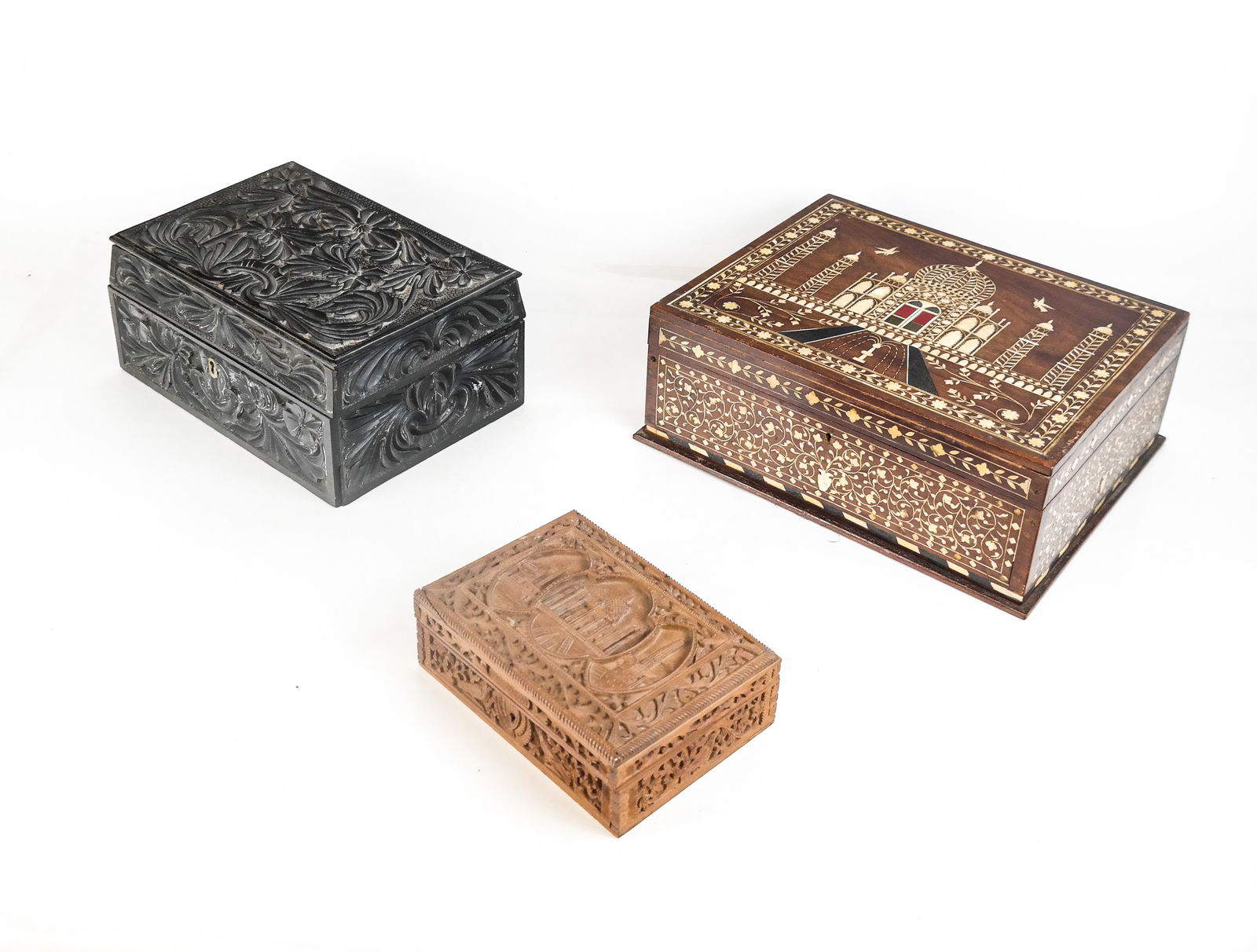 Three Indian Carved and Inlaid Boxes: Thee Indian carved or inlaid boxes comprising a heavily carved an ebonized wood Anglo-Indian box with floral decoration and inlay at inner lid, a carved box with a scene to lid, likely the Taj Mahal,