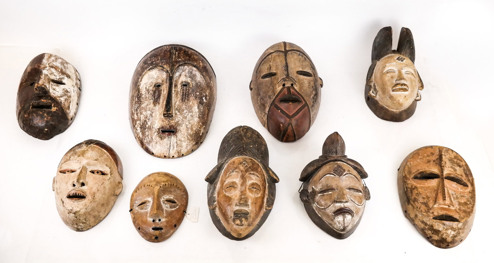 Group of 9 Carved & Painted African Masks: Group of Nine Hand-Carved and Painted African Masks, including examples by the Lega, Fang, Mbuti, Punu, and other peoples. [Largest: 17" H x 10" W; Smallest: 8" H x 6" W]. Varying degrees of wear, ove