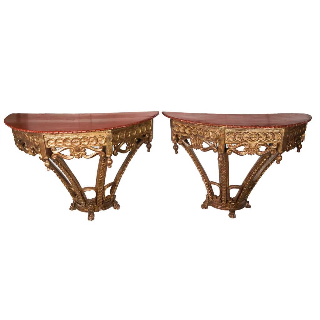 Antique Spanish Neoclassical Giltwood Consoles, Pr: Unusual pair of antique Spanish carved giltwood console tables, late18th century with red paint decorated demilune tops above ornately carved bases with Neoclassical elements. [36" H x 44" W x 26" D].
