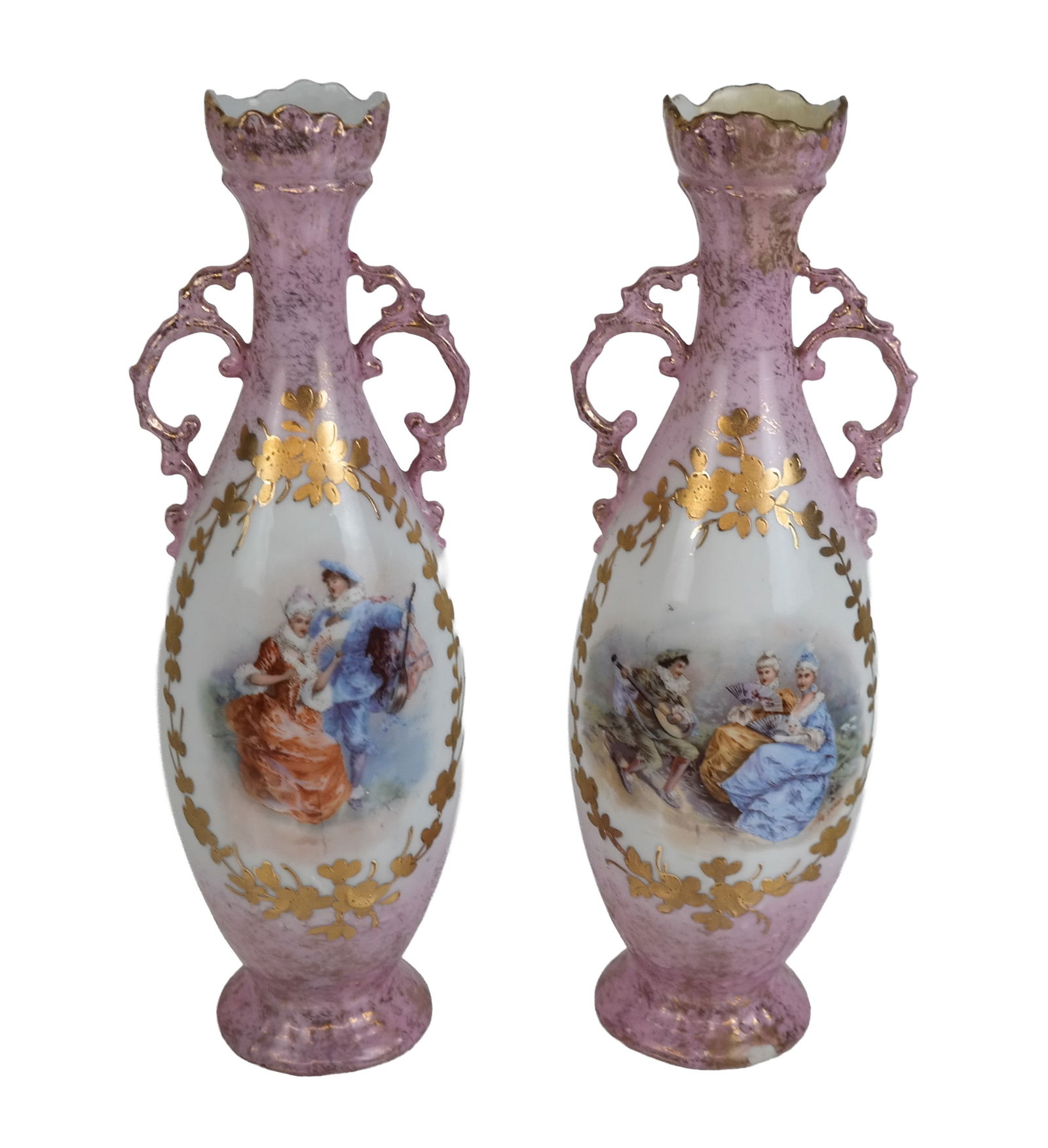 Pair Of Victoria Carlsbad Austrian Vases: Pair of Victoria Carlsbad vases depicting figural scenes on white with gilt and pink trim. [12" H]. One repaired top.