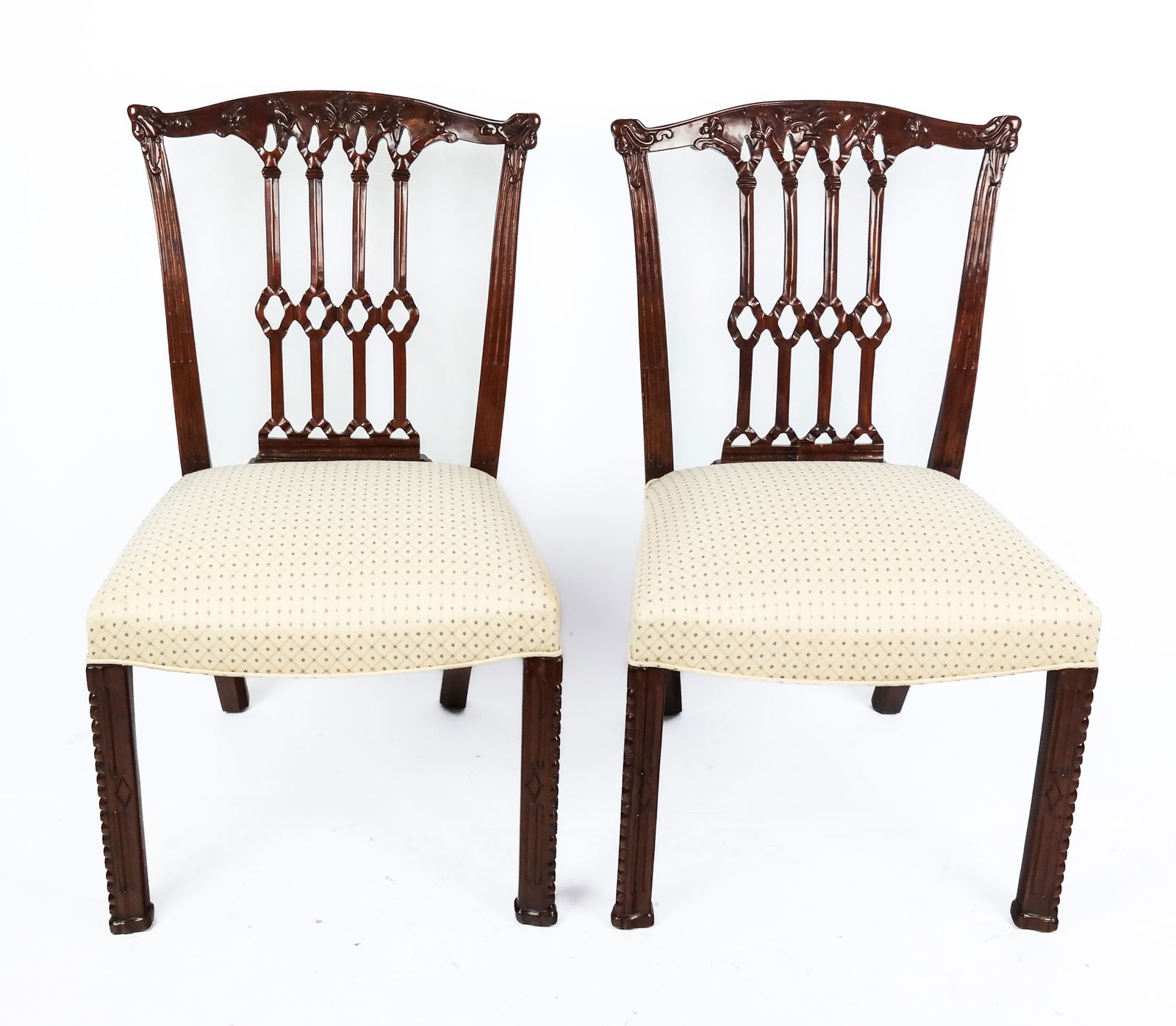 Pair of Georgian Carved Mahogany Side Chairs: Pair of Georgian carved mahogany and upholstered side chairs, late 20th century, the carved back with fleur-de-lis and ribbon detail, above reeded legs. [38.25" H x 22.5" W x 20" D, 19.5" Height to se