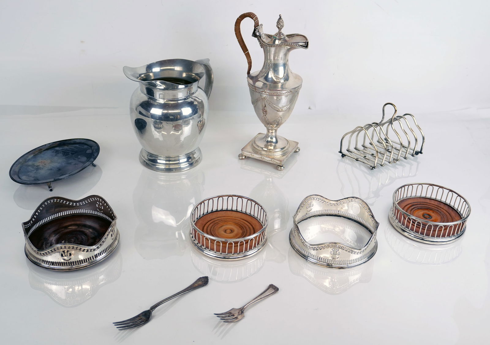 Group of Silver Plate, Pewter and Metal Items, 10: Group of assorted silver plate, pewter, and metal items, comprising pewter pitcher, silver plate demitasse pot, 4 pierced wine coasters, an expandable toast rack, 2 forks, and a patent. Overall condit