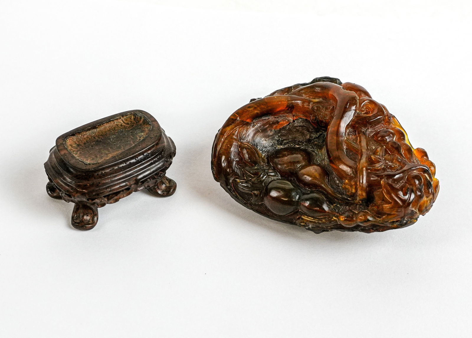 Chinese Carved Amber on Stand: Chinese carved amber, Qing Dynasty, with foliate and gourd decoration, on a carved wooden stand. [Amber: 3" H x 2.5" W x 1.25" D]. Condition is good with some fading and heavy inclusions to amber.