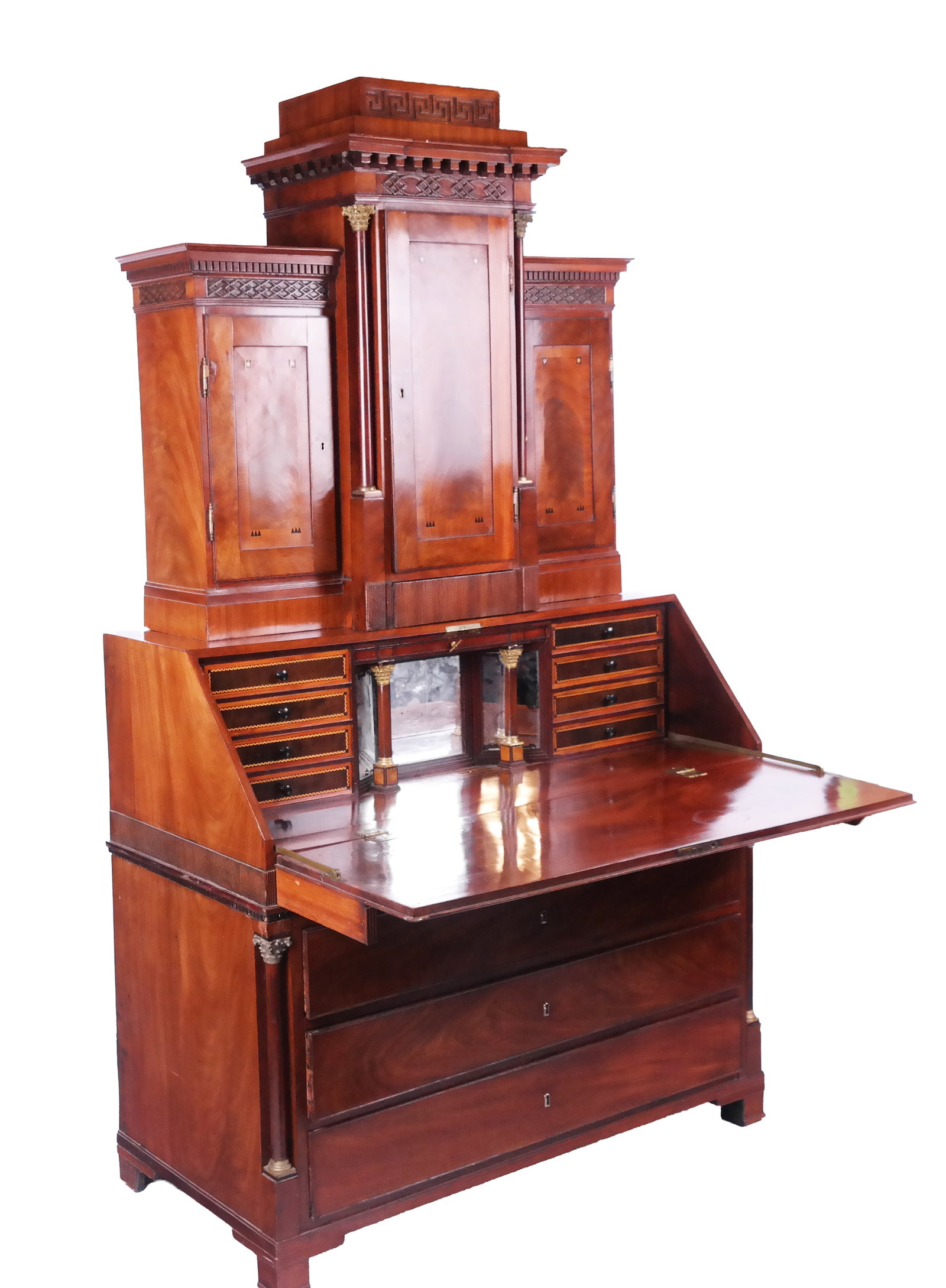 Empire Neoclassical Mahogany Secretary: Empire neoclassical mahogany slant front secretary, late 19th century, the central section with Greek Key and fretwork carved banding opening to reveal shelves, flanked by a lower bookcases with denti