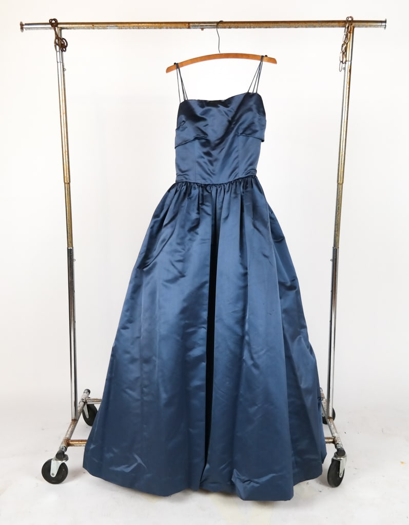 Vintage Blue Gown: Vintage blue gown, mid-20th century, with spaghetti strap over a fitted bodice with an a-line skirt and crinoline lining. [Bust: 15"; waist: 12"; hip: 24"; strap to hem: 61"]. Condition is good with s