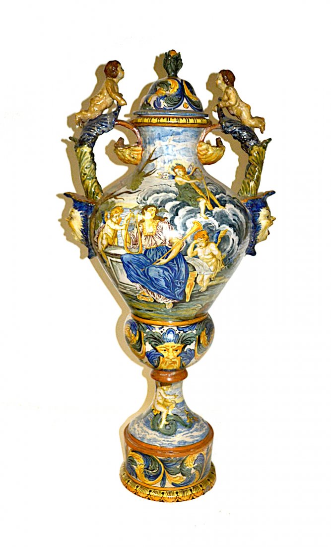 Large Faience Urn-Form Vase: Italian covered vase with figural handles and all-over hand-painted neoclassical vignettes depicting music and love. [17 1/2"W x 13"D x 36 1/4"H] Some repairs, otherwise complete.