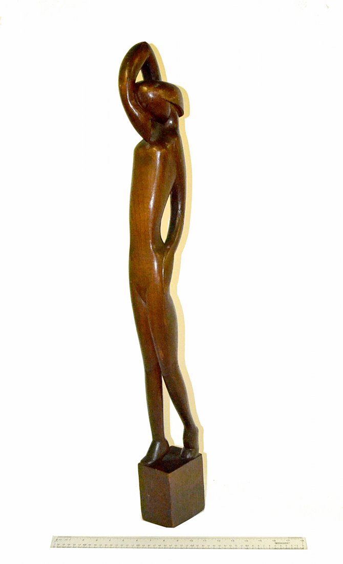 Ivan, Art Deco- Carved Walnut Sculpture: Stylized attenuated depiction of a standing female dancer with raised arm and arched feet. Signed on base "Ivan". [3 1/4"W x 4 1/4"D x 35"H]