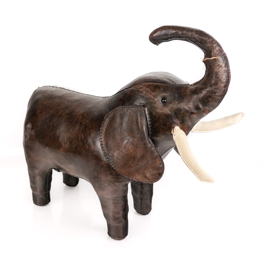 Abercrombie & Fitch Leather Elephant Sculpture: Abercrombie & Fitch leather elephant sculpture / footstool, unmarked. [18.5" H x 20" L x 9" D]. Overall condition fair, one tusk loose, trunk with tear and missing stuffing, wear commensurate with age