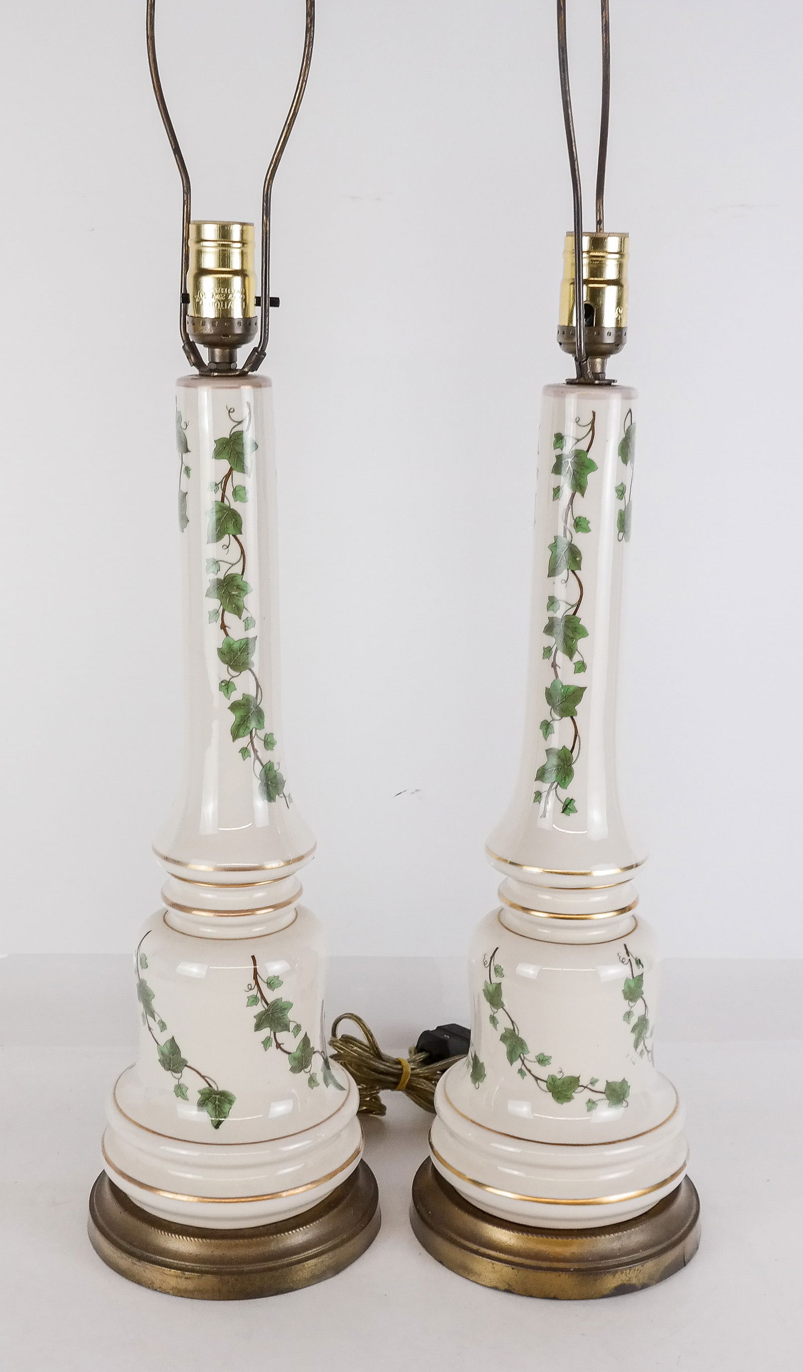 Pair Of Porcelain Leaf-Decorated Lamps: Pair of white porcelain lamps with leaf and vine decoration and gold trim. [18" H (to socket) x 6.5" Diameter (base)].