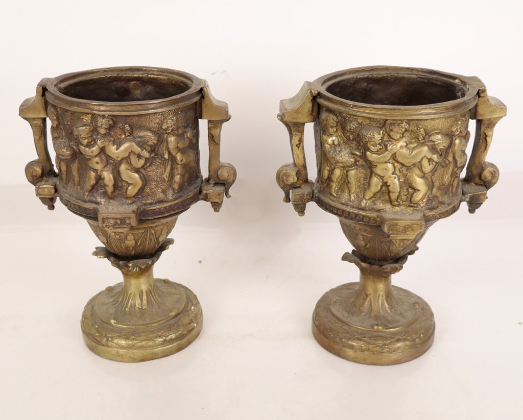 Pair of French Gilt Bronze Urn Jardinieres: Pair of gilt bronze pedestal urn form jardinieres, 20th century, with a Bacchic frieze of putti to upper, with two handles, and a laurel and acanthus decorated pedestal base. [9" H x 8" W x 6" D]. Con