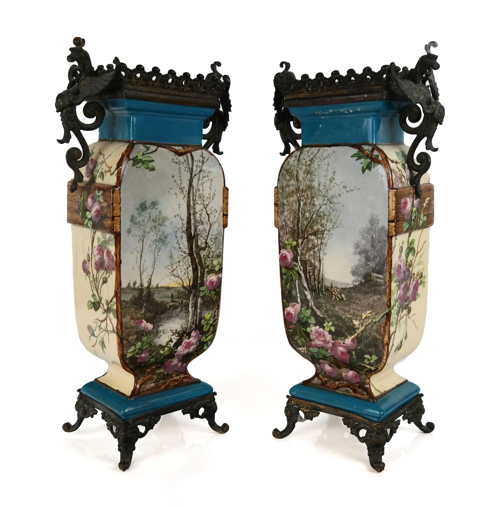 Pair of Continental Hand-Painted Metal Vases: Pair of hand-painted enamel scenic vases mounted with griffin handles and scrolling metal feet, bases signed KF 20 with maker's mark. [ 15.25" H x 7.5" W x 4" D]. Overall condition is fair, enamel