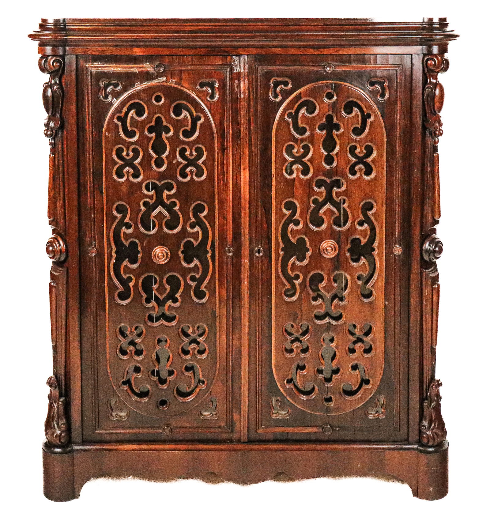 Victorian Carved Rosewood Fretted Cabinet: Victorian carved rosewood and fretwork cabinet, 19th century, with two doors opening to reveal four shelves at interior, carved mounted sides with scrolls and crests, and carved skirt. [54" H x 47" W