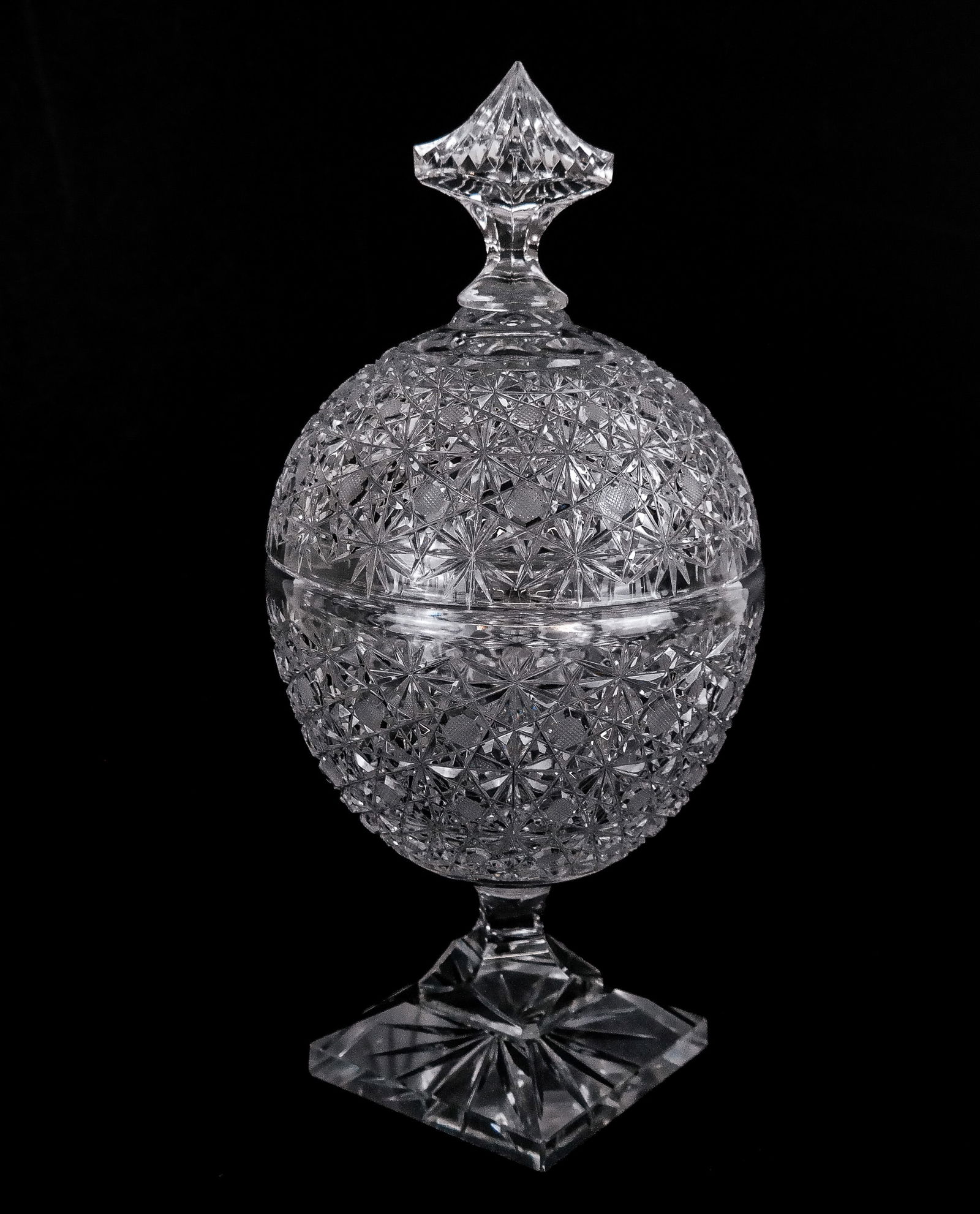 American Brilliant Period Cut Glass Sweet Meat Dis: American Brilliant Period cut glass sweet meat dish, of egg shape form, with pagoda type finial and resting on a square base, unsigned. [13.5" H x 6" Diameter]. Overall condition is good, with
