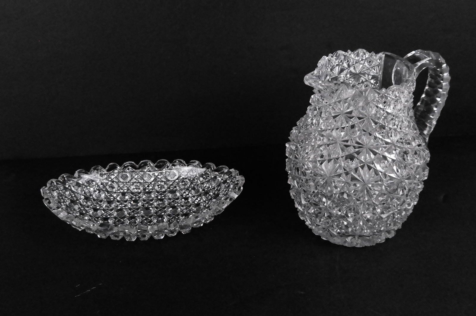 American Brilliant Period Cut Glass Pitcher and Ov: American Brilliant Period cut glass pitcher [7.5" H x 7.5" W x 6" D], and an oval relish tray [1.75" H x 8.5" L x 5" D]. Overall condition is good/fair, pitcher with scratches to base and minor chip