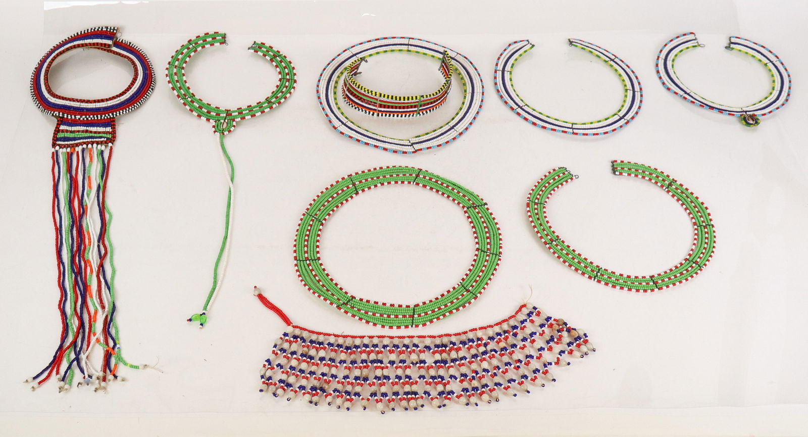 Collection of Maasai-Inspired Beaded Collars, 9: Collection of Maasai-inspired beaded collars, in various styles and colors. [Largest in green, red and white beads: 10" Diameter]. Overall condition is good, some with wear and bent wire.