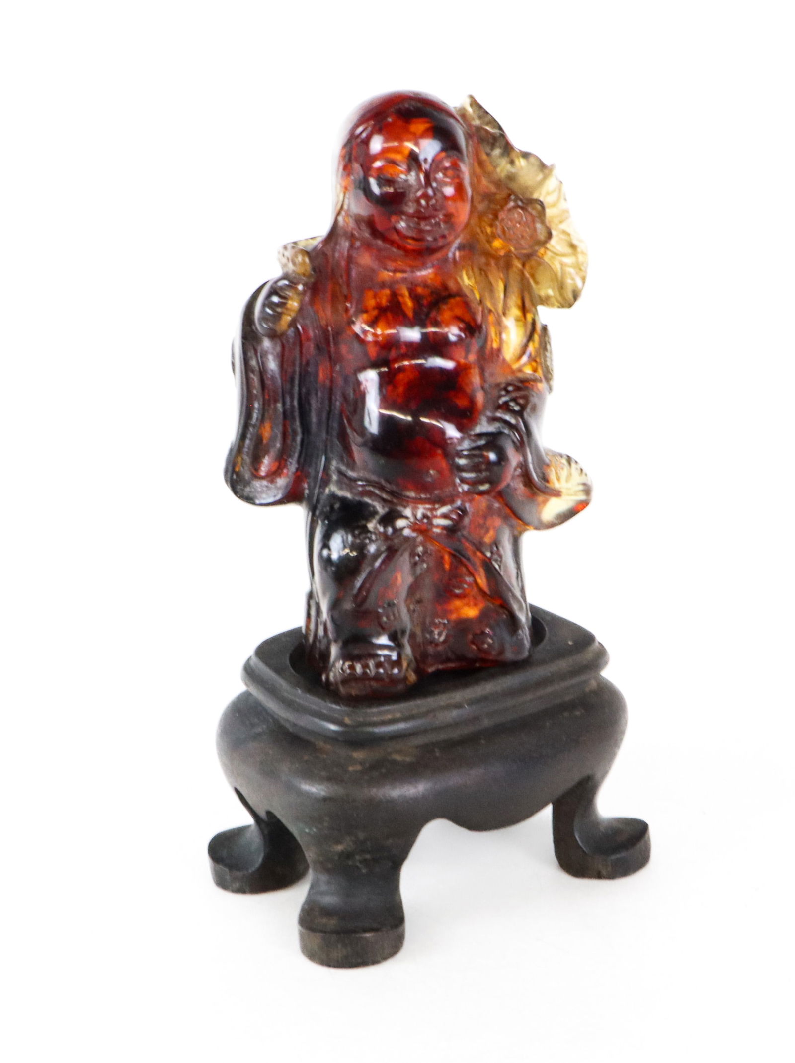 Chinese Carved Amber Figure of Buddha: Chinese carved amber figure of Buddha, 20th century, holding a lotus leaf, on an affixed wooden stand. [Less stand: 3.5" H x 2" W x 1.75" D] Condition is good with some wear.