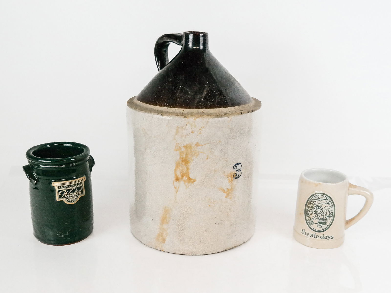 American Ceramic Articles, 3: Three articles of American ceramics including a jug, a cannister marked Wooloch, and a Cermarte Stein with inscription to one side. [Large jug: 16" H x 10.5" Diameter]. Condition is good to fair with