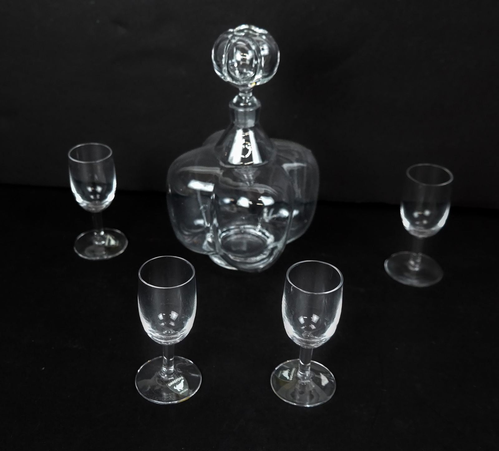 Orrefors Petite Cordial Set, 5: Orrefors petite cordial set, Swedish, 20th century, comprising a crystal decanter and four glasses, some with affixed Orrefors label, otherwise unmarked. [Decanter: 7.25" H x 4" Square]. Condition is