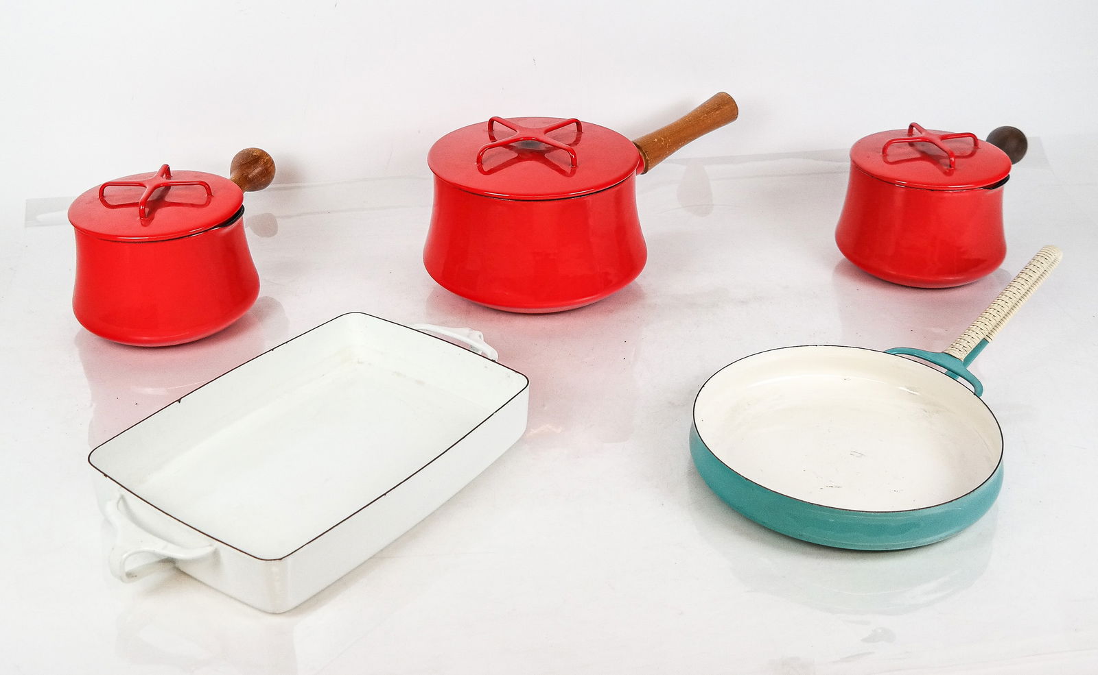 Dansk Enamel Cookware, 5: Dansk enamel cookware, comprising three red sauce pans with lids [Largest: 6" H x 14" L x 7.5" W], a turquoise enamel paella pan with braided handle, and white enamel double handled baking pan [2" H