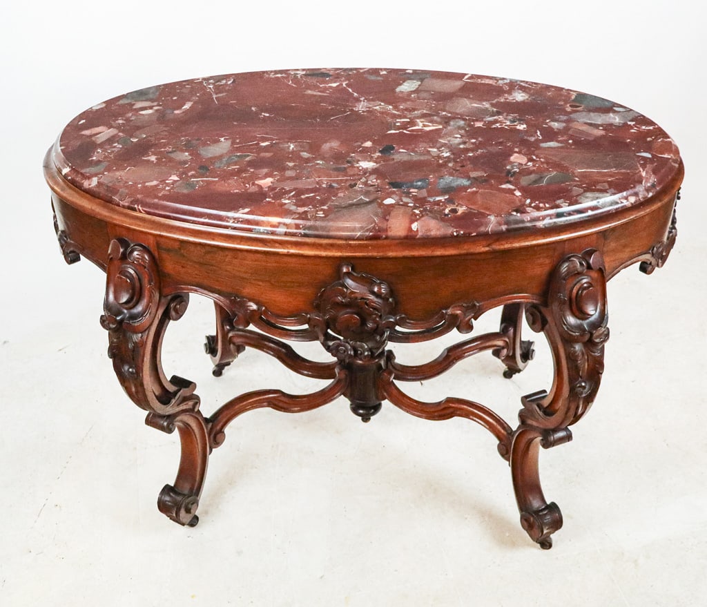 Victorian Rosewood Marble Top Center Table: Victorian marble top table, 19th century, with red marble to upper, over a carved rosewood base joined at lower by a cross stretcher. [31" H x 48" W x 28" D]. Condition is good with some minor wear.