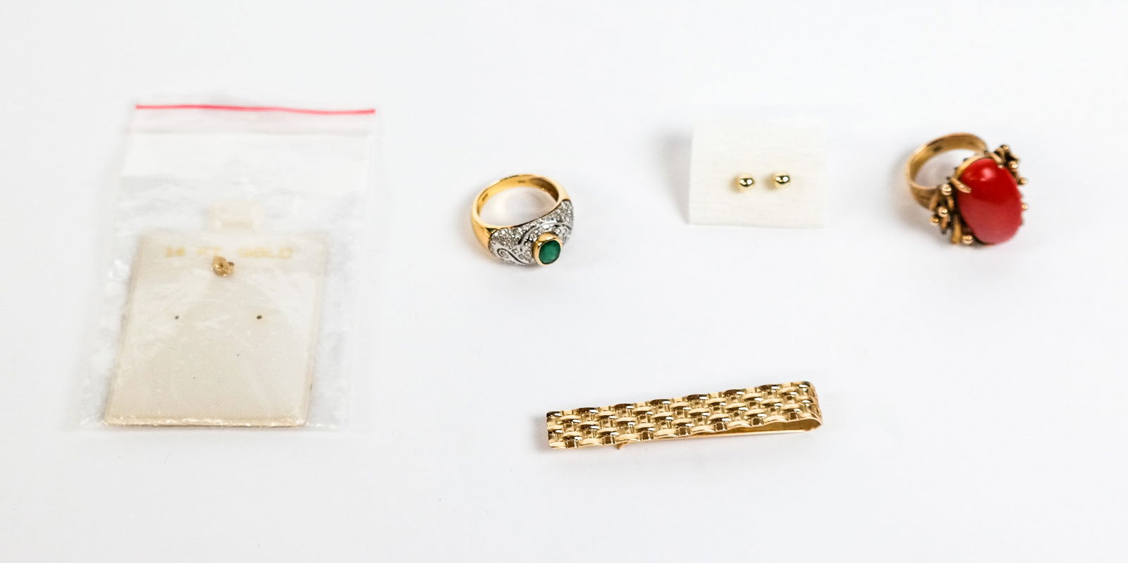 Group of Gold Jewelry: Group of 14K gold jewelry, comprising a modernist coral ring, an emerald and diamond ring, tie tack and pair of tiny bead earrings, all marked "14K". [Total 14.83 dwt., Tie tack: 2" L]. Overall