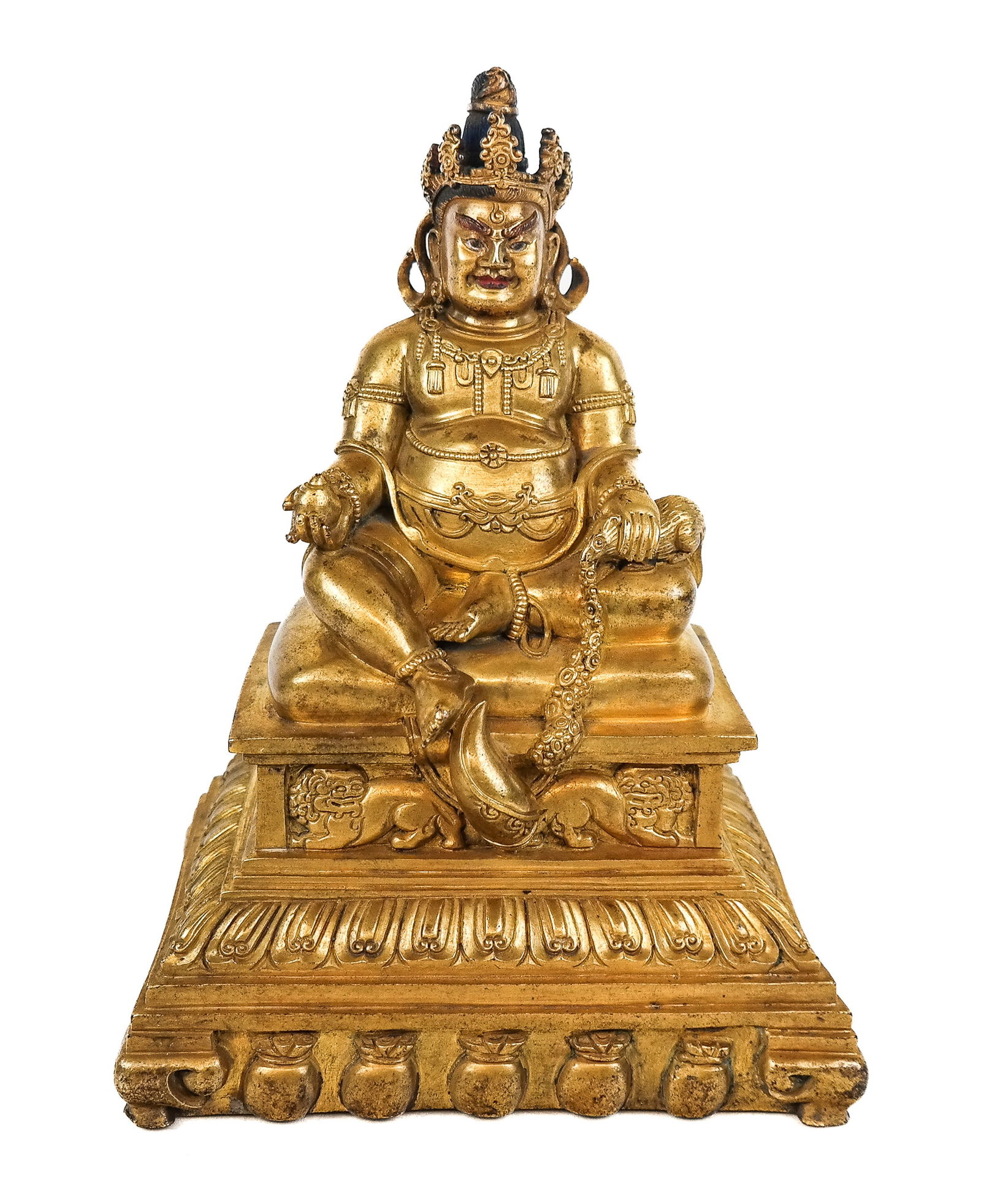 Tibetan Gilt Bronze of a Seated Jambhala: Tibetan gilt bronze of a seated Jambhala (Dzambhala), 19th century, with painted details, and holding a mongoose and a conch, a and seated on a decorative base with foo dogs and a decorated foot, mark