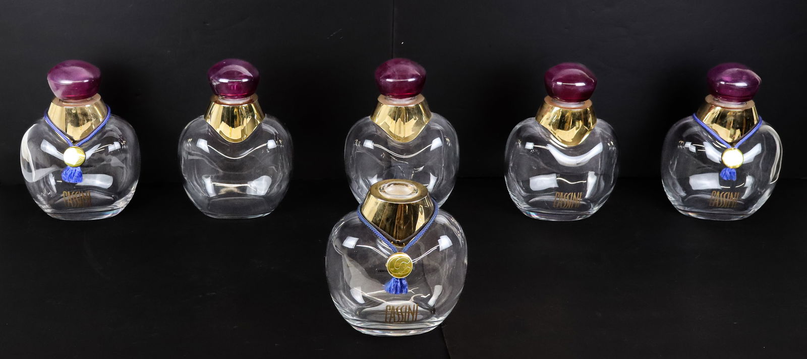 Six "Cassini" Dummy Model Large Perfume Bottles: Set of six "Cassini" dummy model decorative large perfume bottles, five with pink glass tops, one unmarked. [9.75" H x 7" W x 5" D]. Overall condition varies, sold as is.