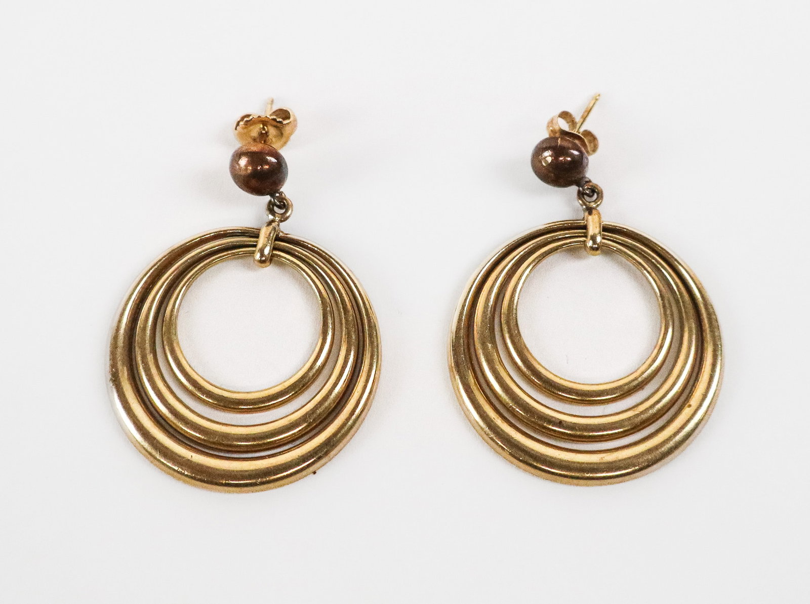 Pair of Gold Ear Pendants: Pair of 14K gold earrings, designed as button posts suspending three concentric ring, unmarked by tested for 14K gold. [Total 8.47 dwt., 1.5" H x 1" W]. Overall condition is good/fair, require cleanin
