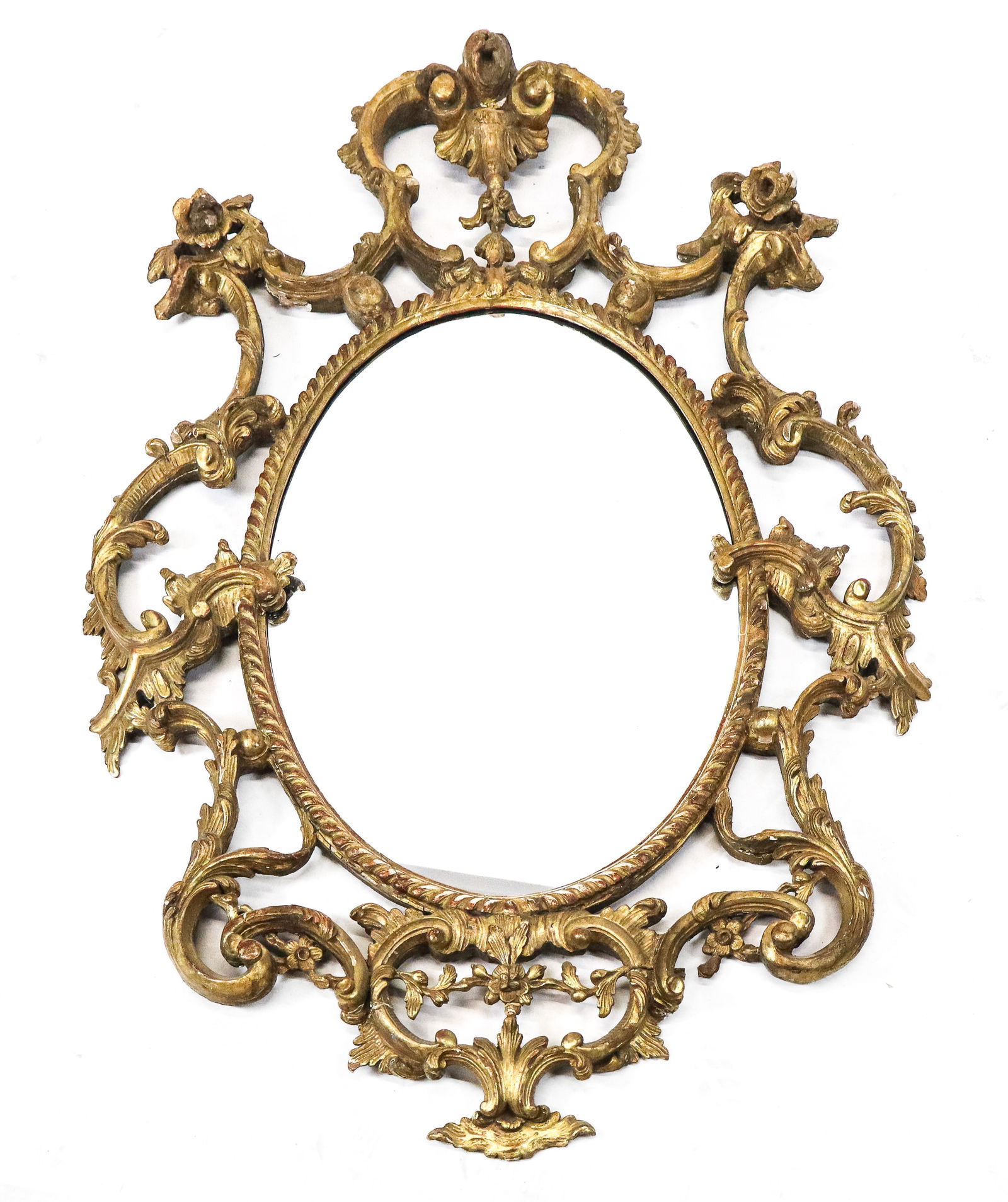 Antique Gilt Carved Mirror: Antique gilt carved mirror, early 19th century, oval gadroon trim frame with elaborate open gilt carvings of scrolls and waves, with high floral and upper corner floral carvings, and bottom of a shell