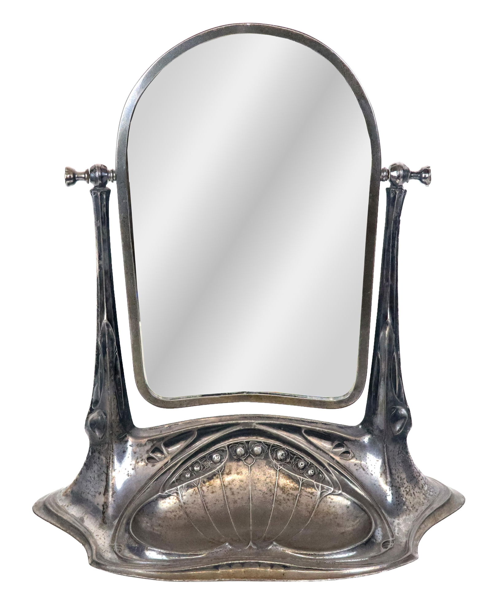 Art Nouveau Silver Plate Vanity Mirror: Art Nouveau silver plate vanity mirror, early 20th century, with rose decoration to lower and a tray, and a beveled glass mirror supported by organic arms, unmarked. [20" H x 17" W x 9" D]. Condition