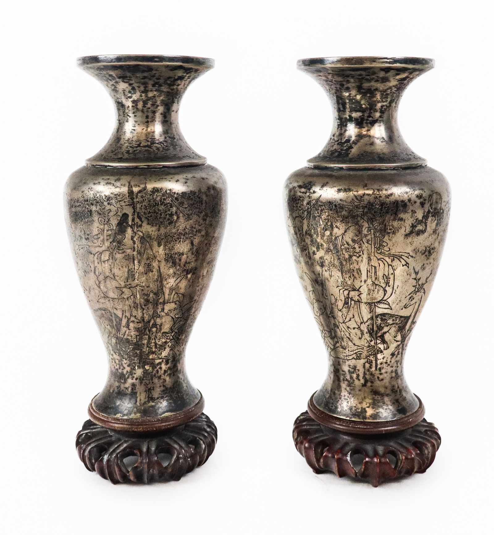 Pair of Chinese Silvered Decorated Vases: Pair Chinese silvered metal vases on wood stand, the vases with black outlined designs of figures and animals. [10" H x 4.5" Diameter]. One dent on one vase, bases screw off.
