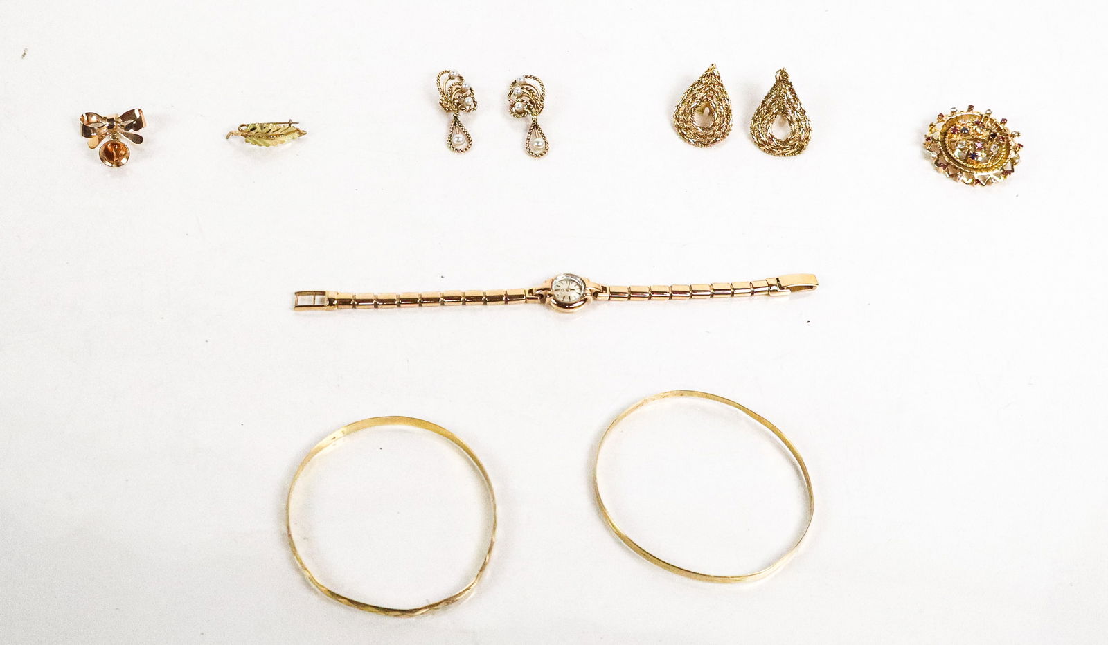 Collection of Gold Jewelry, 10: Collection of 18K gold jewelry, comprising two pair of earrings - one accented with cultured pearls, a small leaf, two bangle bracelets, an Egyptian bow brooch, an Ebel Egyptian ladies wristwatch, and